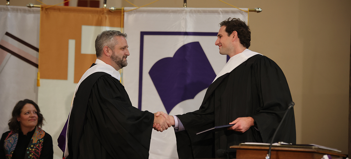 An alumnus at the lecturn of the Methodist church greets another almunus to congratulate him on his alumni award. The college chaplain is in the background.
